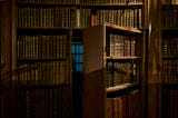 A secret door disguised as a bookcase in a library opens to reveal a room inside.