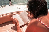 A person reads a book on a hot summer day while she lay relaxed on a boat in the ocean. Cryptocurrency