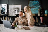 A man and woman looking at a laptop.