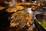 Okonomiyaki frying on a hotplate.