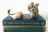 Brass book ends of a whale and squirrel seating on two vintage books