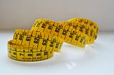 Yellow measuring tape on neutral background