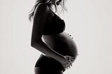 A pregnant woman in backlight.