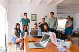 A team working together, huddled around an employees screen