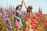 Two women in a field of flowers.