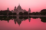 Image of Victoria Memorial in Kolkata, India at sunset with a red sky in the background reflecting red off the water