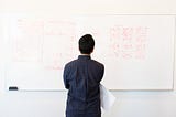Image of a person standing in front of a whiteboard filled with sketches