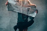A person leaning against a wall reading a newspaper. The paper is on fire.
