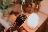 Burning sage with lite crystal lamp in the background