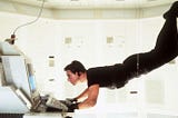 Captivating still from the 1996 Paramount Pictures’ Mission Impossible film, featuring Ethan Hunt (Tom Cruise) suspended on a wire, conducting a high-stakes operation on a state-of-the-art computer within a secure, hermetically sealed facility.