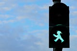 Photo of the green for “go” state on a German pedestrian signal from former East Germany. It shows the outline of a man in a hat.