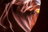 A desert cave, carved out of stone, with light filtering in through the opening.