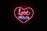 neon sign of heart with words inside: love 24 hrs