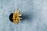 Looking down on an open dark cup of plain yellow pencils on a blue-gray textured background