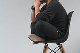 Man sitting side-on on a chair thinking