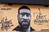 Grey-scale mural of George Floyd on a plywood covered storefront with the words “I Can’t Breathe!” “Stand United” and “Stop the Violence”