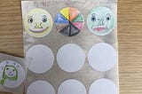 three emoji’s created by a young person. One is yellow with a happy face. One is green with a straight face. One is a circular rainbow.