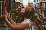 Woman looking through bookshelves in a bookstore.