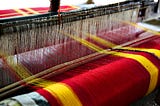 handloom machine weaving red and yellow threads