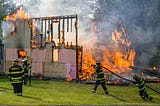 Fire fighters controlling a house on fire. The image is evocative of my childhood memory of watching the house next to us in Punjab on fire.