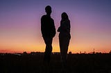 Silhouetted couple standing apart at sunset — visual metaphor for emotional distance in relationships when seeking fulfillment only God can provide, illustrating the key concept from ‘Why Your Spouse Can’t Be Your Messiah’ article about marriage expectations and spiritual needs