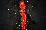 picture shows the chilli is cut into various parts and displayed on the black surface and sprinkled with water