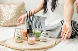 Woman with crossed legs sitting in front of candles and incense