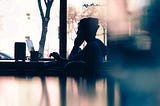 Silhouette of a man sitting at a table looking at a laptop