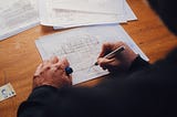 A man at a desk drawing on architectural blueprints