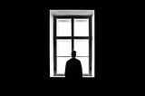 Lonely person in dark room looking through window