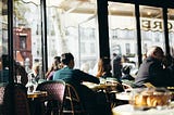 Inside the Café de Flore, customers enjoying drinks and pastries, with a view out the cafe window.