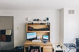 A desk with two monitors in a college dorm room