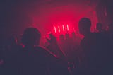 People in a room with red lighting.