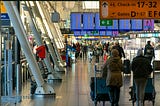 People pushing luggage in an airport terminal.