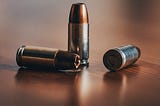 Close-up of three rounds of 9 mm hollow point lay randomly on a table top.