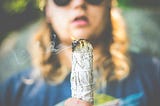 A young woman — presumably a Gen Z-er — stares meditatively at what appears to be a clump of burning sage.