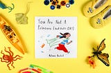 A children’s book surrounded by buttons, slippers and such