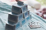 A house of blue backed cards with a few extra playing cards facing up next to them.