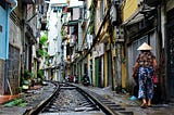 A woman is walking by the railroad tracks in a narrow street in Hanoi