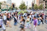 Blurred images of people crossing a busy sidewalk