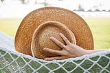 woman with straw hat laying in hammock