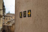 Little images of a crescent moon, the star of David and a cross on a wall.