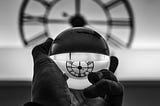 an image of a hand holding a ball that is reflecting a clock