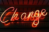 An electric sign glowing orange that says change.