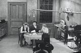 TV set of 1950s sitcom, The Honeymooners, showing main characters sitting around kitchen table in a very drab Brooklyn apartment
