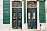 A pair of very similar front doors with ironwork