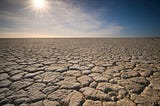 Flat, dry, parched earth under a bright sun.