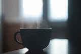 A small teacup with steam radiating from it