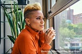 Black woman thinking deeply over a cup of coffee at the window