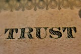 A closeup picture of the word Trust on a United States dollar.